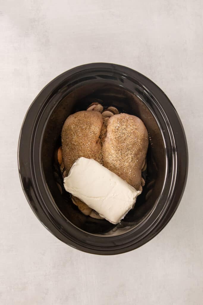 a black crock pot filled with chicken and cheese.