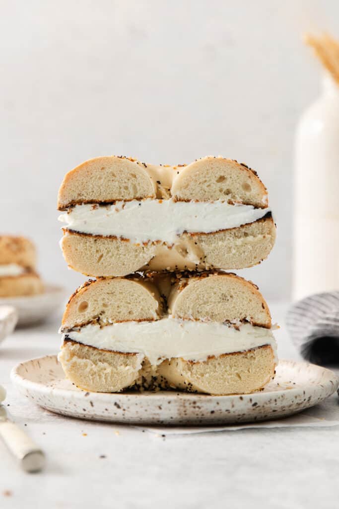 a stack of bagel sandwiches with cream cheese on top.