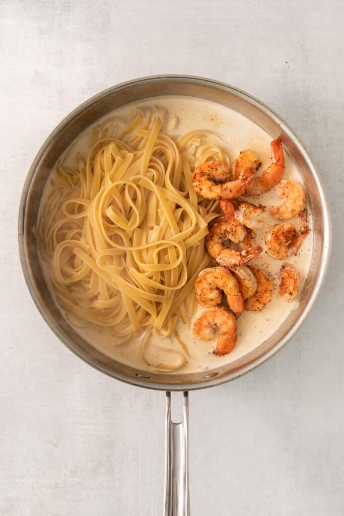 shrimp and pasta in a pan on a white background.