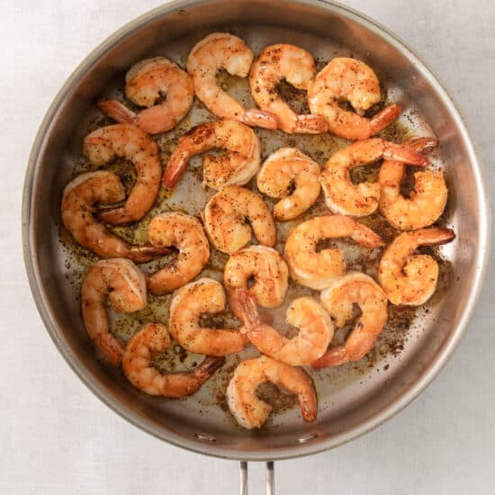 grilled shrimp in a skillet on a white background.