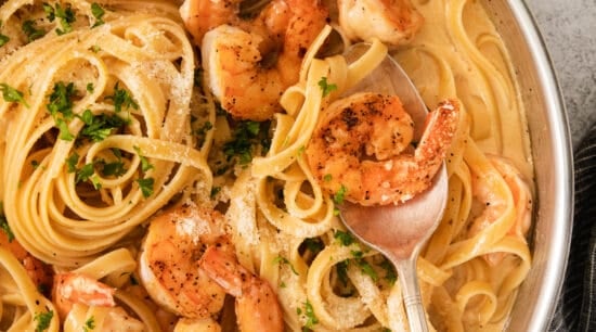shrimp pasta in a pan with a spoon.