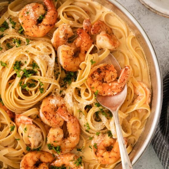 shrimp pasta in a pan with a spoon.