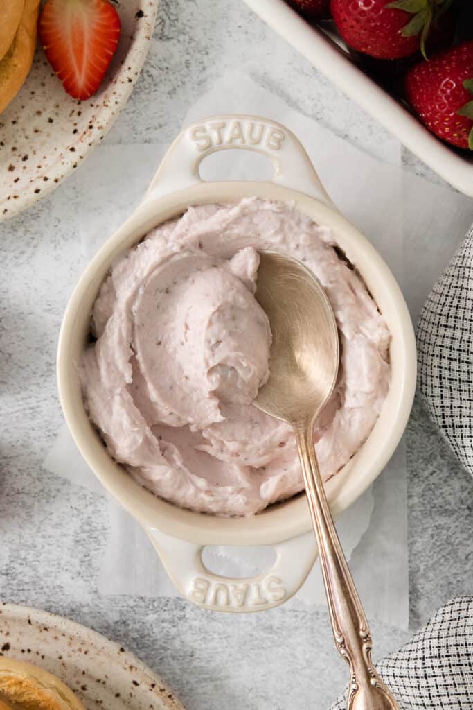 strawberry whipped cream in a white bowl with a spoon.