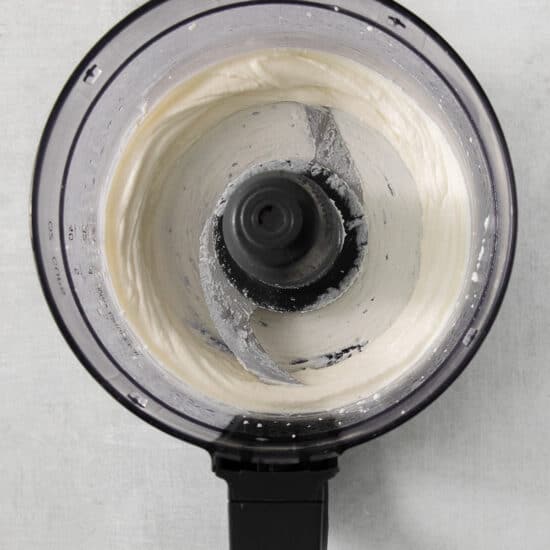 a food processor with a white liquid in it.