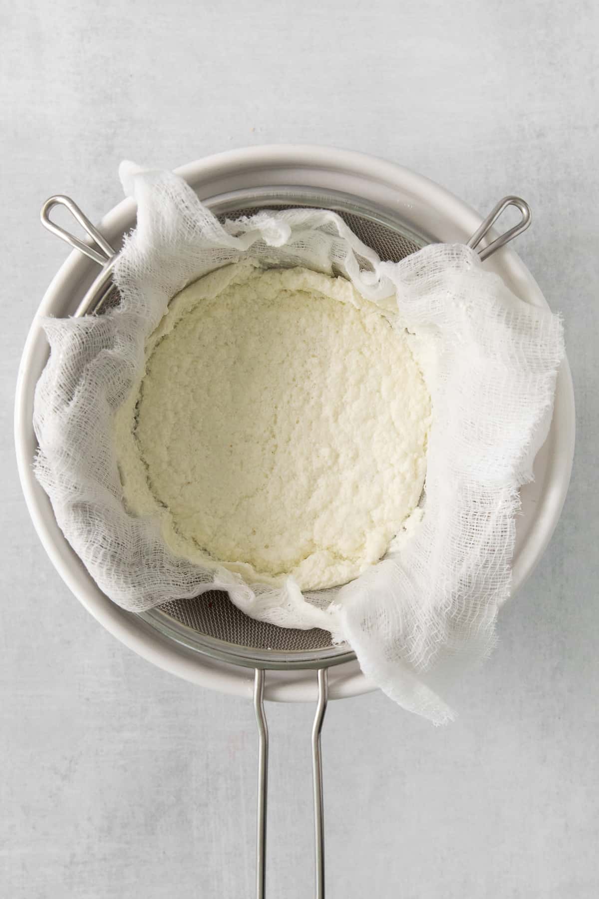 a white cloth is placed over a bowl of cheese.