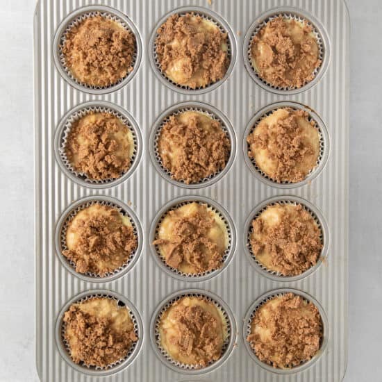 a muffin pan filled with muffins with a crumb topping.