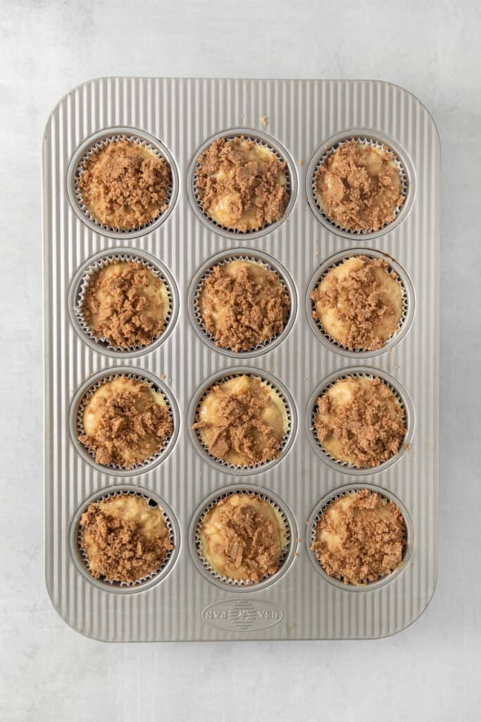 a muffin pan filled with muffins with a crumb topping.