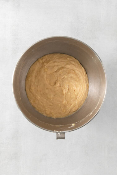 a metal bowl filled with batter on a white surface.