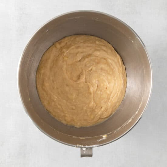 a metal bowl filled with batter on a white surface.