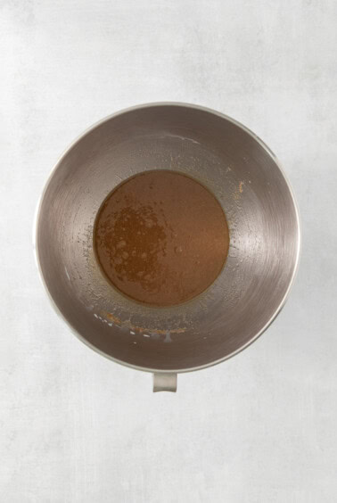 brown sauce in a metal bowl on a white surface.