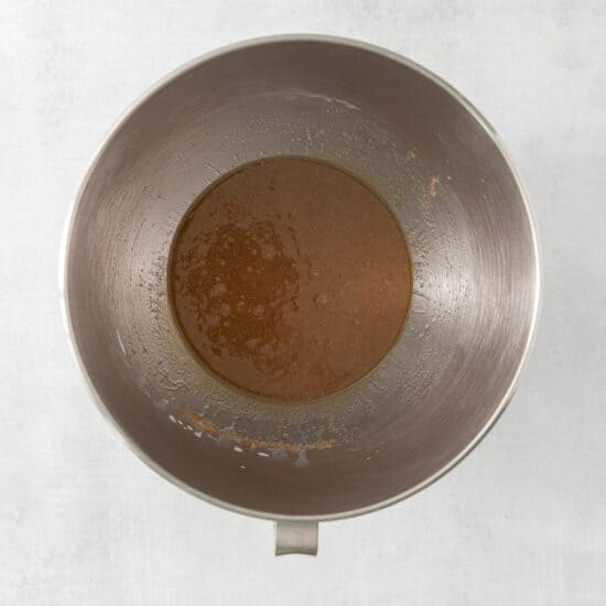 brown sauce in a metal bowl on a white surface.