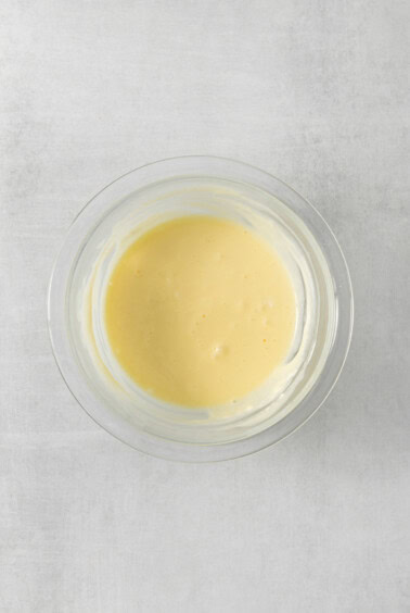 a bowl of yellow sauce on a white surface.