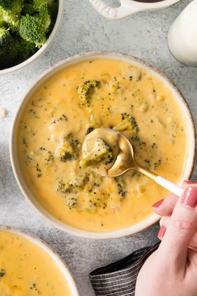 a bowl of broccoli cheese soup with a spoon.