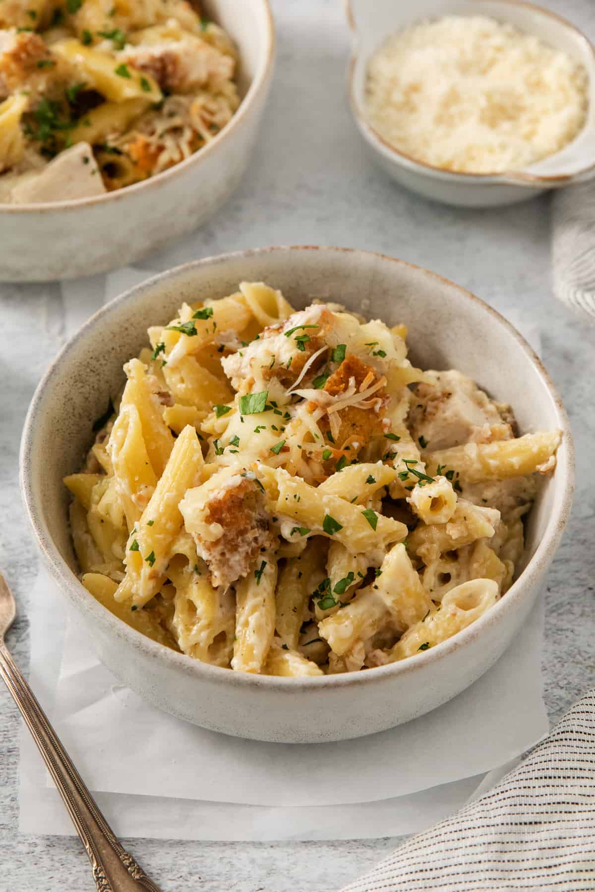 two bowls of pasta with chicken and parmesan.