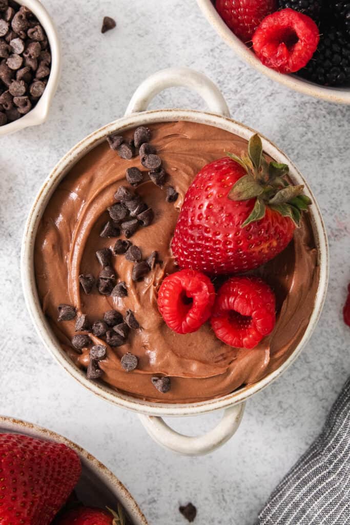 a bowl of chocolate pudding with strawberries and chocolate chips.