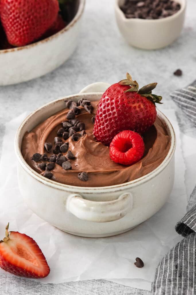 a bowl of chocolate pudding with strawberries and chocolate chips.