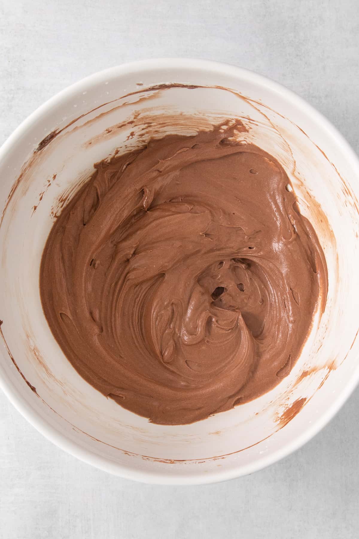 a white bowl filled with chocolate frosting on top of a table.