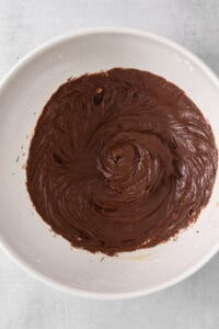 a white bowl filled with chocolate frosting on top of a table.