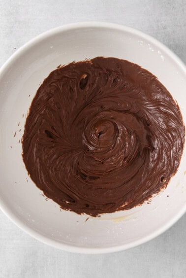 a white bowl filled with chocolate frosting on top of a table.