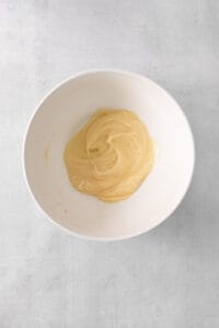 a white bowl with a yellow substance in it.