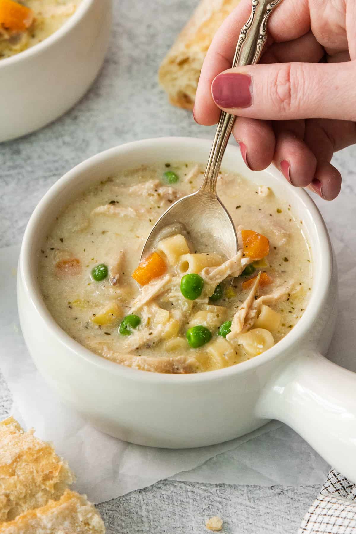 a spoonful of chicken noodle soup in a white bowl.