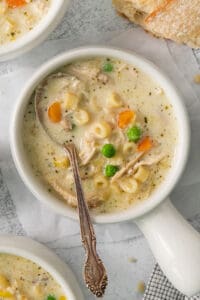 chicken noodle soup in a white bowl with a spoon.