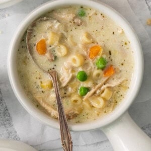 chicken noodle soup in a white bowl with a spoon.