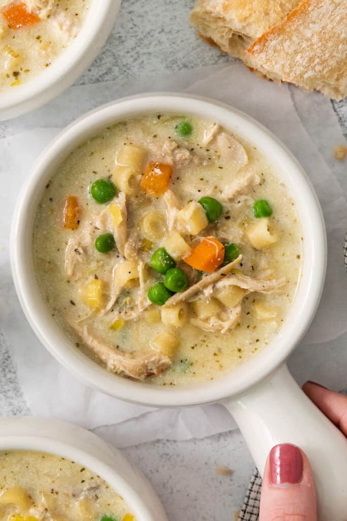 a bowl of chicken noodle soup with peas and carrots.