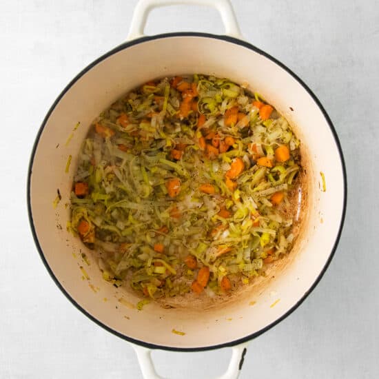 a pot filled with carrots and brussels sprouts.