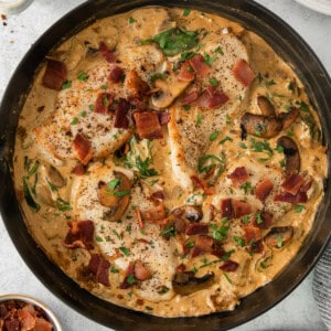 a skillet filled with chicken, bacon and mashed potatoes.