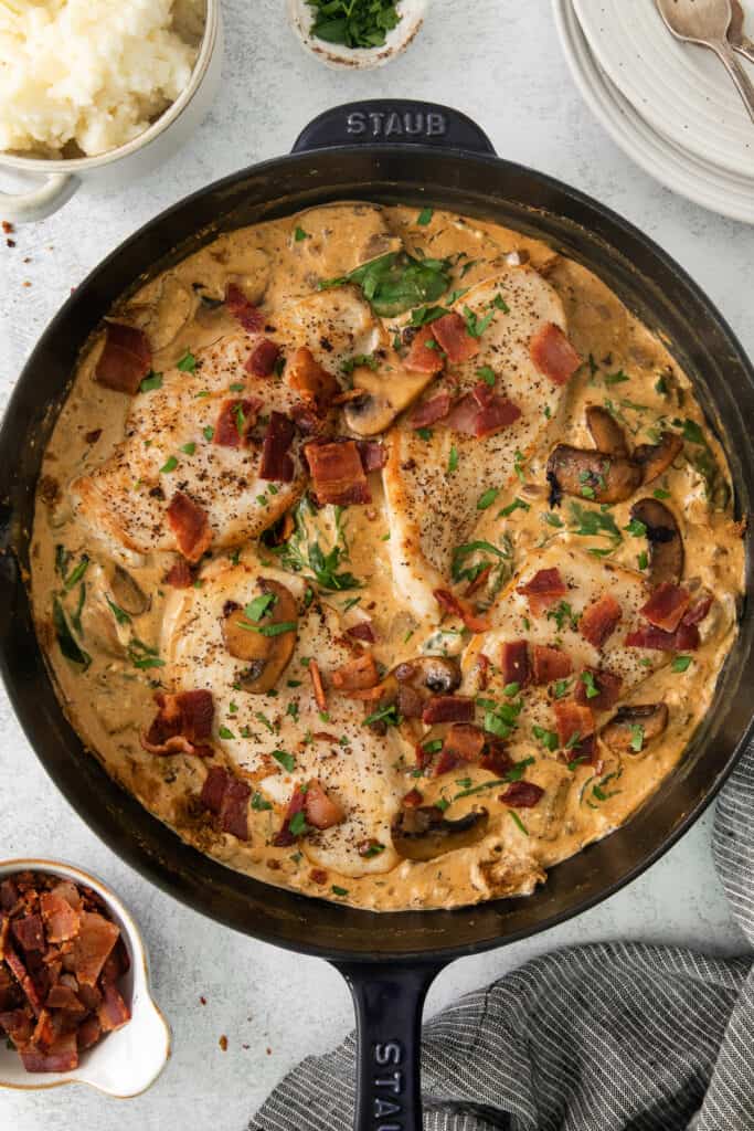 a skillet filled with chicken, bacon and mashed potatoes.