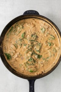 a skillet with chicken and spinach in it.
