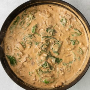 a skillet with chicken and spinach in it.