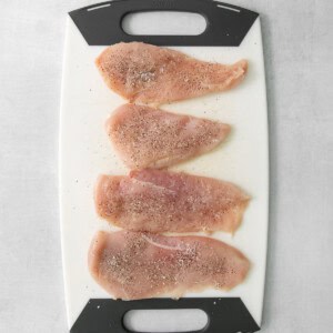 four pieces of chicken on a cutting board.