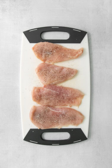 four pieces of chicken on a cutting board.