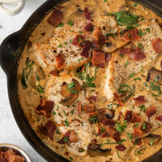 a skillet filled with chicken, bacon and mushrooms.