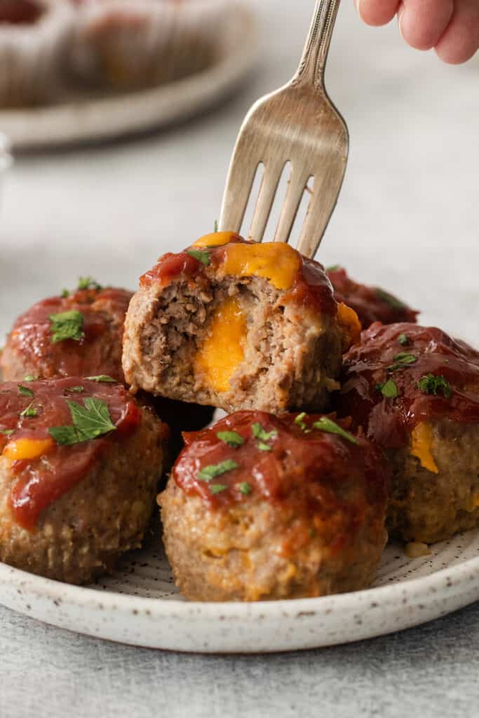 cheesy meatballs on a plate with a fork.