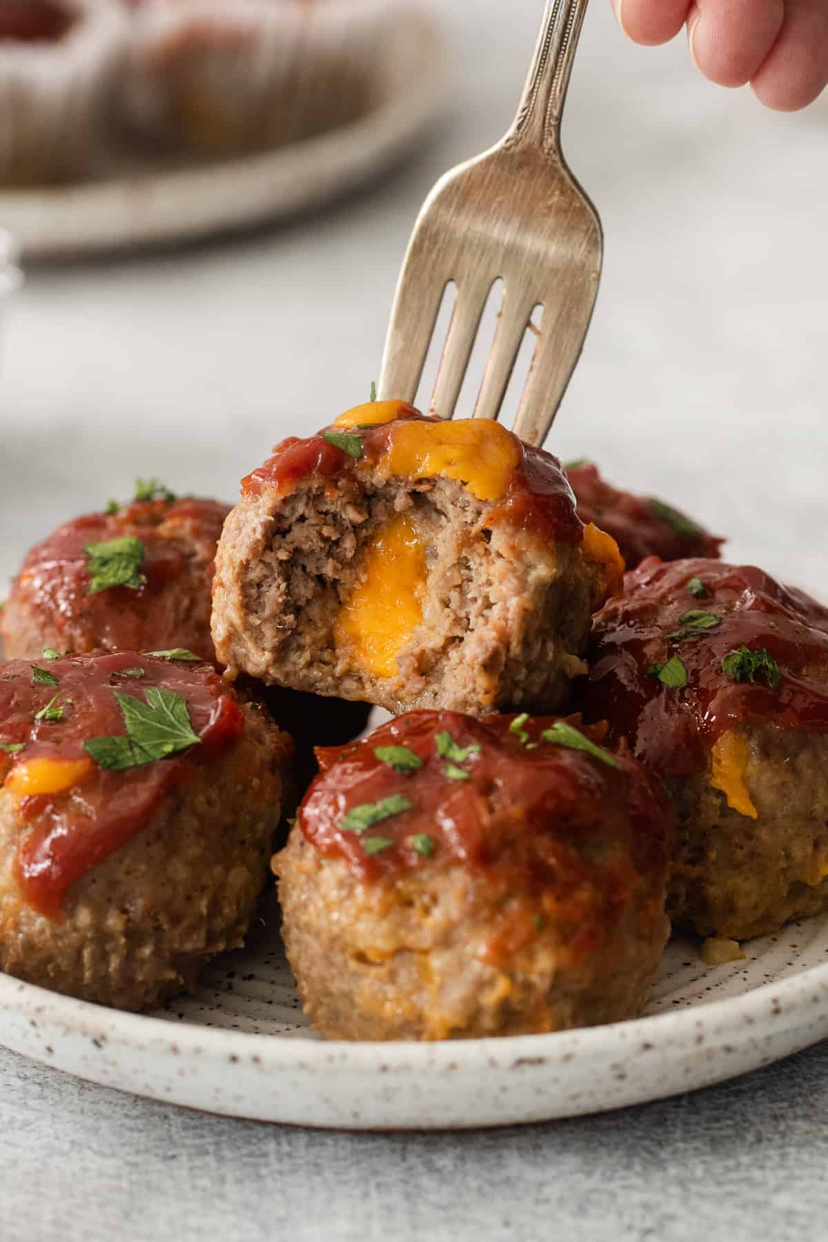 cheesy meatballs on a plate with a fork.