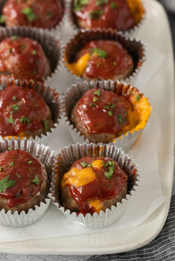 meatballs in foil cups on a white plate.