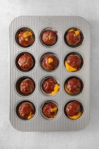 a muffin tin filled with meatballs and cheese.