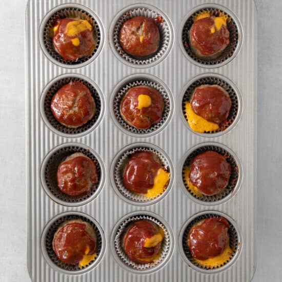 a muffin tin filled with meatballs and cheese.