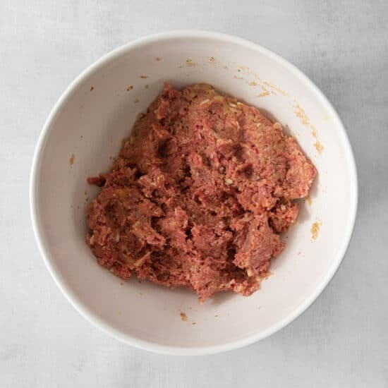 ground beef in a bowl on a white surface.