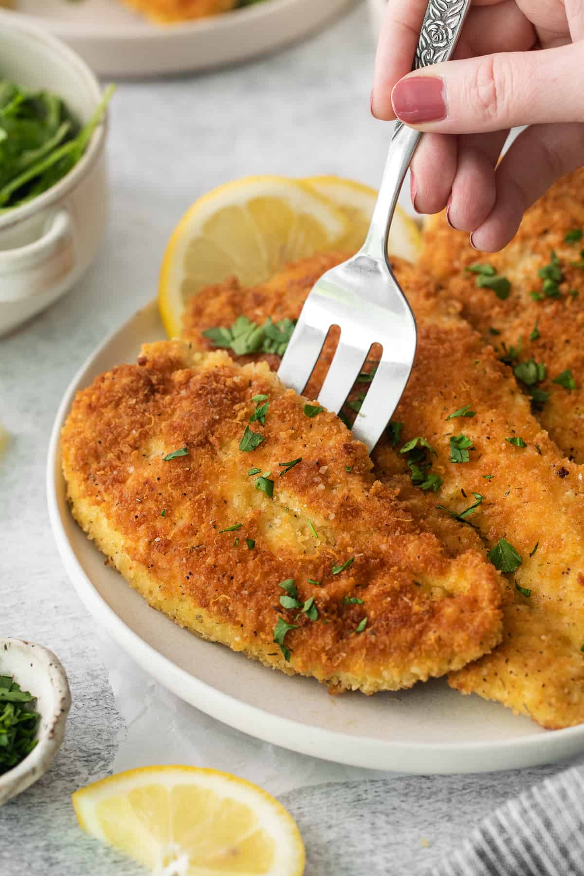 a person holding a fork to a plate of fried chicken.