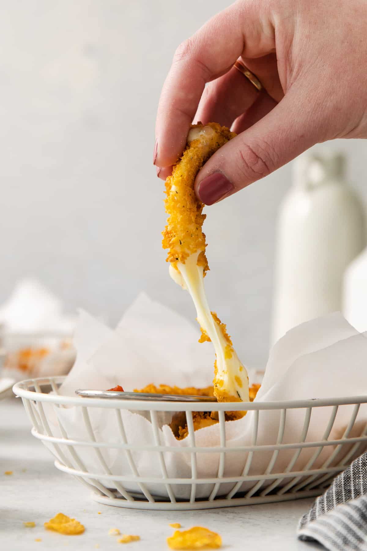 a person dipping a piece of cheese into a basket.