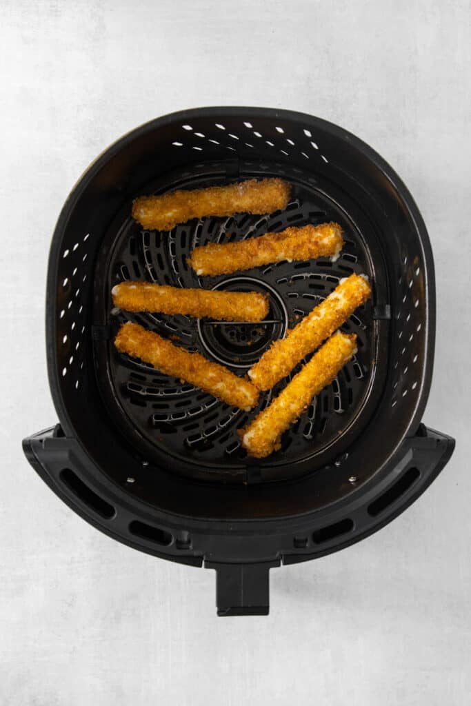 a black air fryer with fries in it.