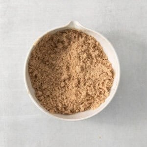 a white bowl filled with brown sugar on top of a table.