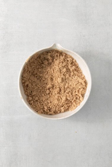 a white bowl filled with brown sugar on top of a table.