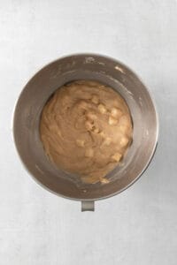 a metal bowl filled with peanut butter on top of a table.