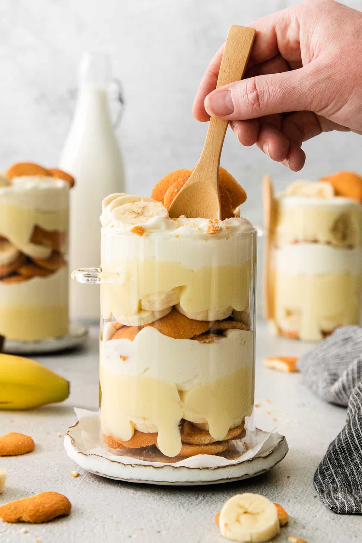 a person holding a wooden spoon over a layered dessert.