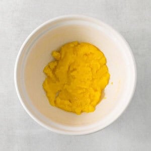 a white bowl filled with yellow food on top of a table.